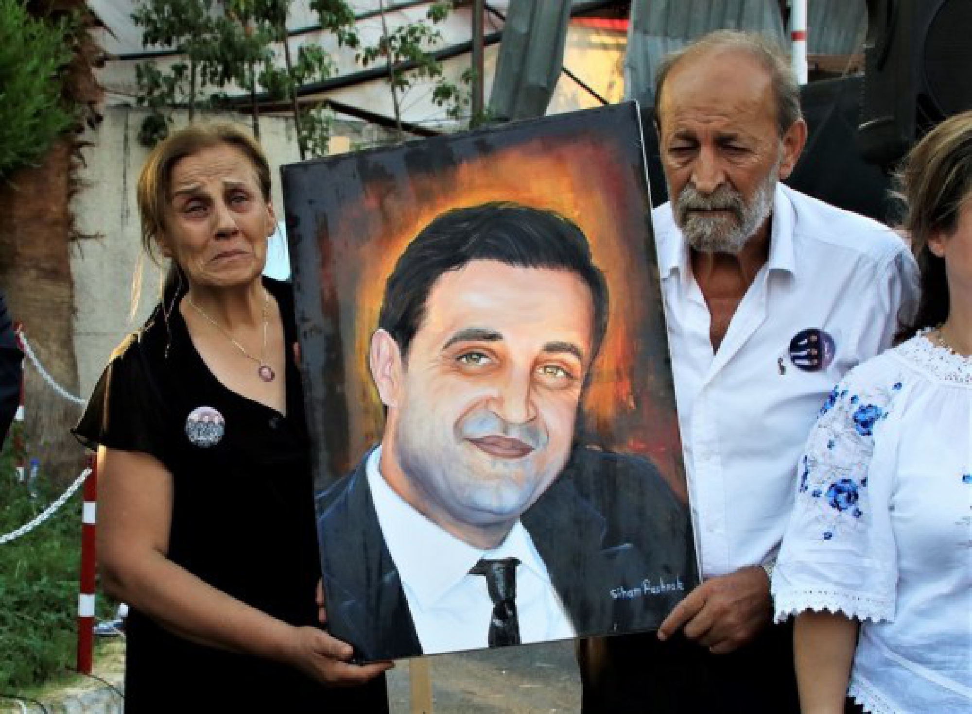 Family members of a firefighter martyr are offered his portrait at an art exhibition commemorating the martyrdom of 10 firefighters upon the first anniversary of the Beirut port blast in Beirut, Lebanon, Aug. 3, 2021.