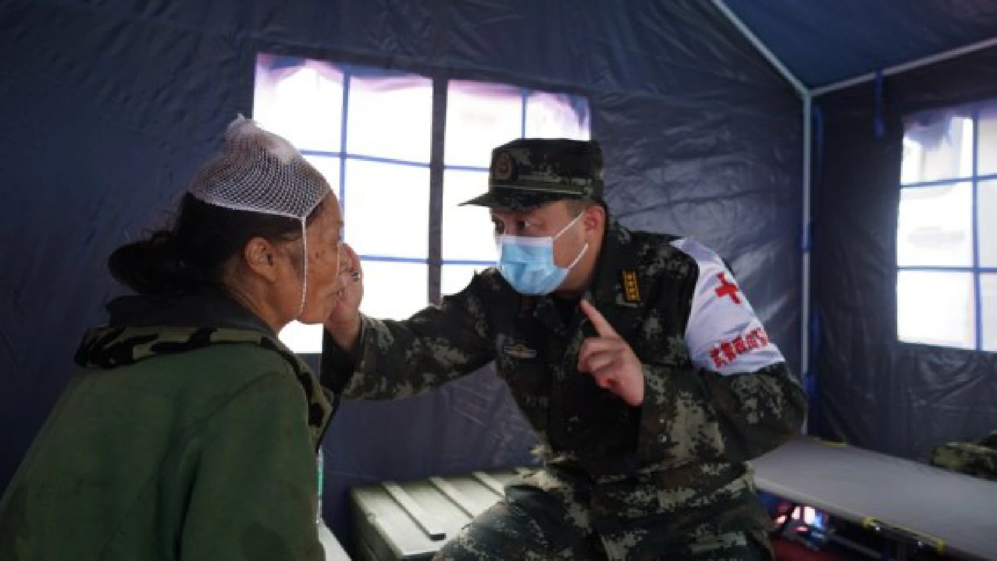 An armed police medic treats an injured woman at a relocation site in Fuji Township, Luxian County, southwest China's Sichuan Province, on Sept. 16, 2021. (Xinhua/Yang Jin)