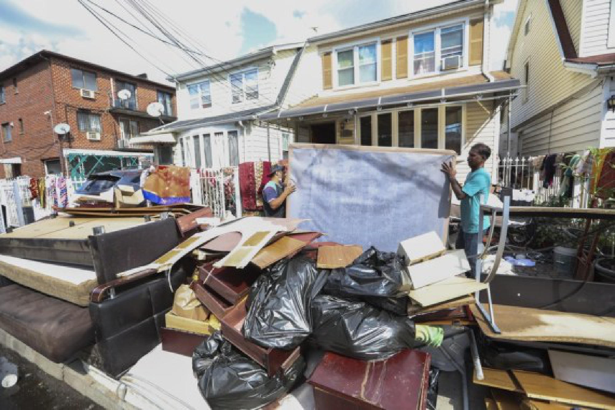 People move waterlogged belongings outside a house, in the Flushing neighborhood of the Queens borough of New York, the United States, Sept. 3, 2021.
