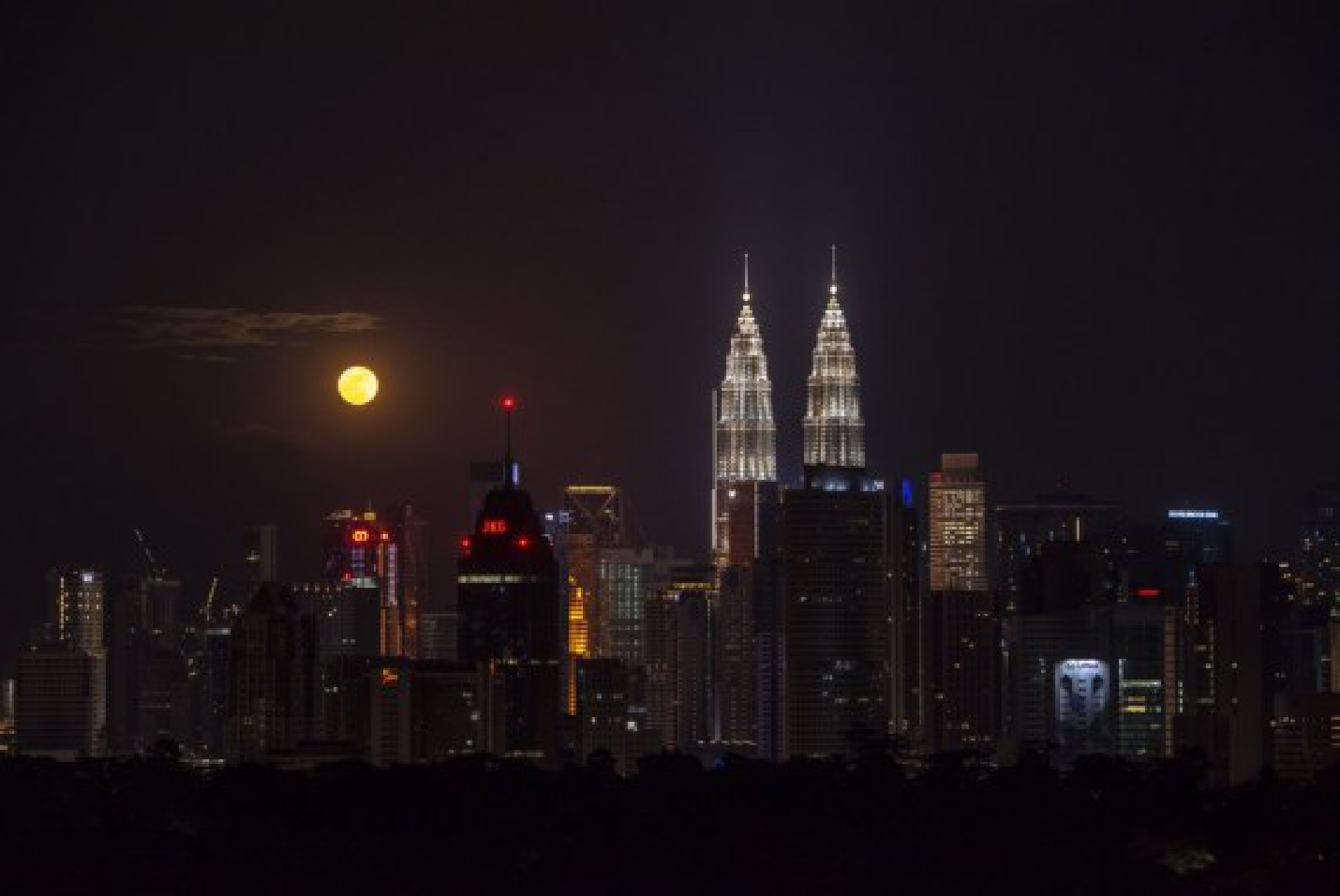 A full moon is seen against the skyline of Kuala Lumpur, Malaysia, on the occasion of Mid-Autumn Festival on Sept. 21, 2021. (Photo by Chong Voon Chung/Xinhua)