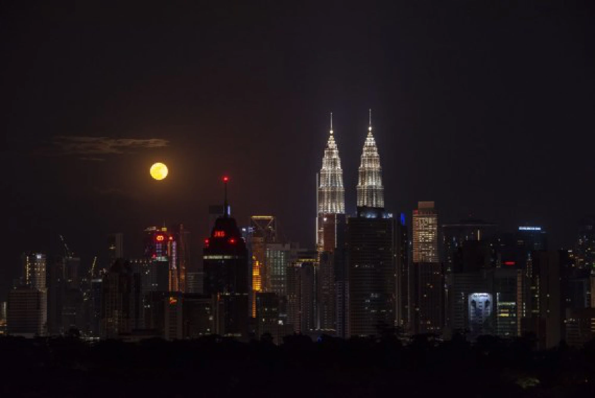 A full moon is seen against the skyline of Kuala Lumpur, Malaysia, on the occasion of Mid-Autumn Festival on Sept. 21, 2021. (Photo by Chong Voon Chung/Xinhua)