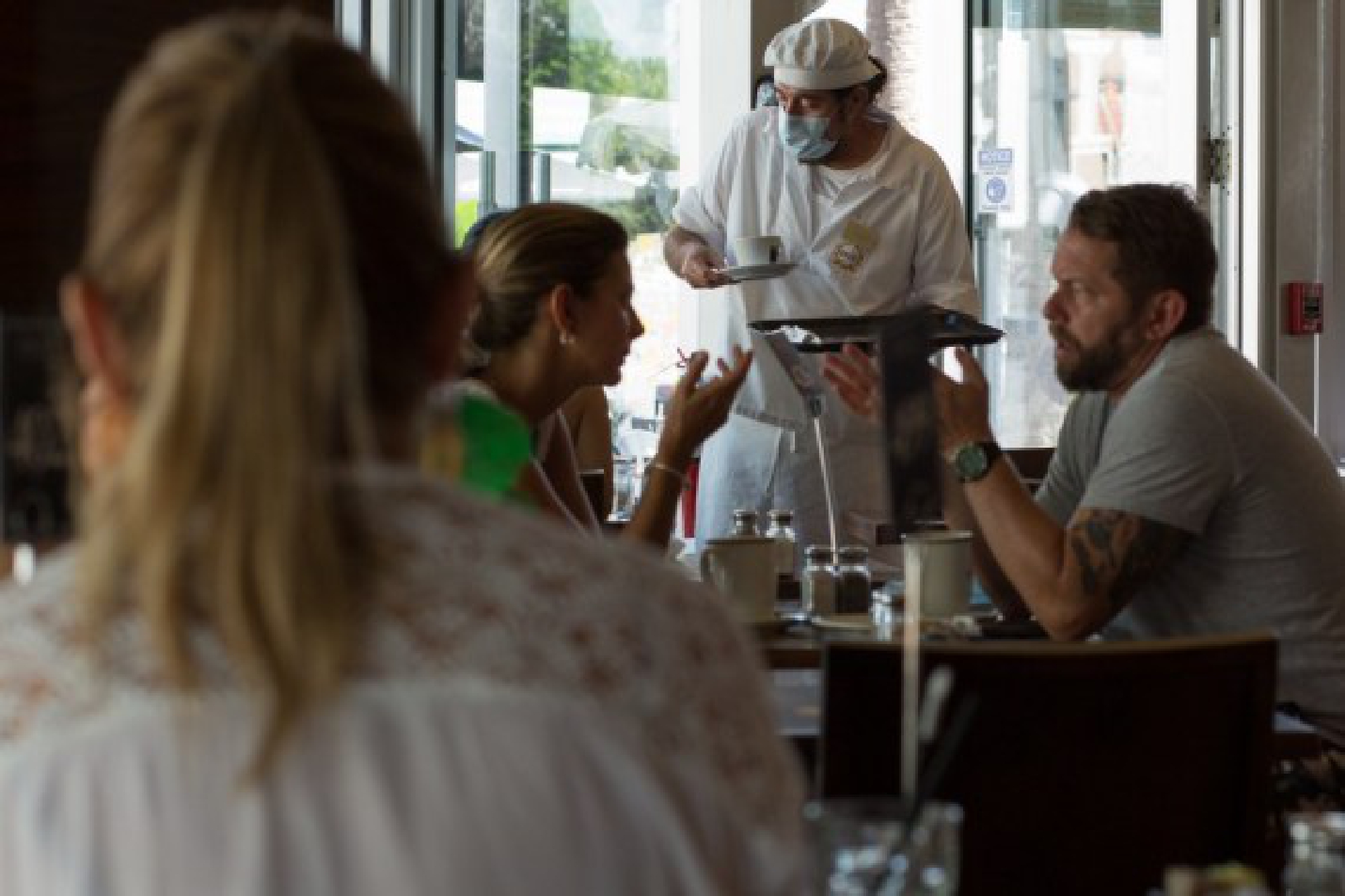A waiter wearing a mask serves the customers at a restaurant in Miami-Dade County, Florida, the United States, Aug. 6, 2021. (Photo by Monica McGivern/Xinhua)