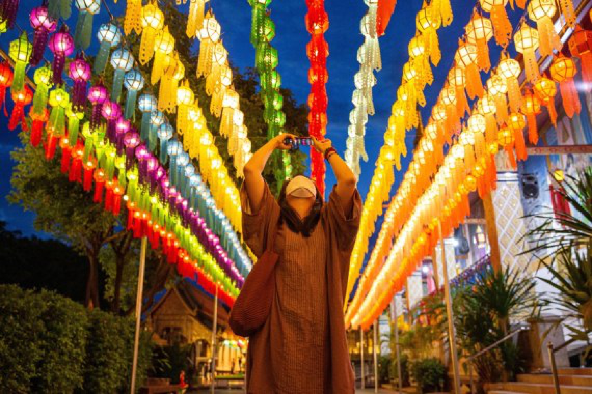 A tourist takes photos of lanterns at the Wat Phra That Hariphunchai in Lamphun, Thailand, Oct. 25, 2021. (Xinhua/Wang Teng)