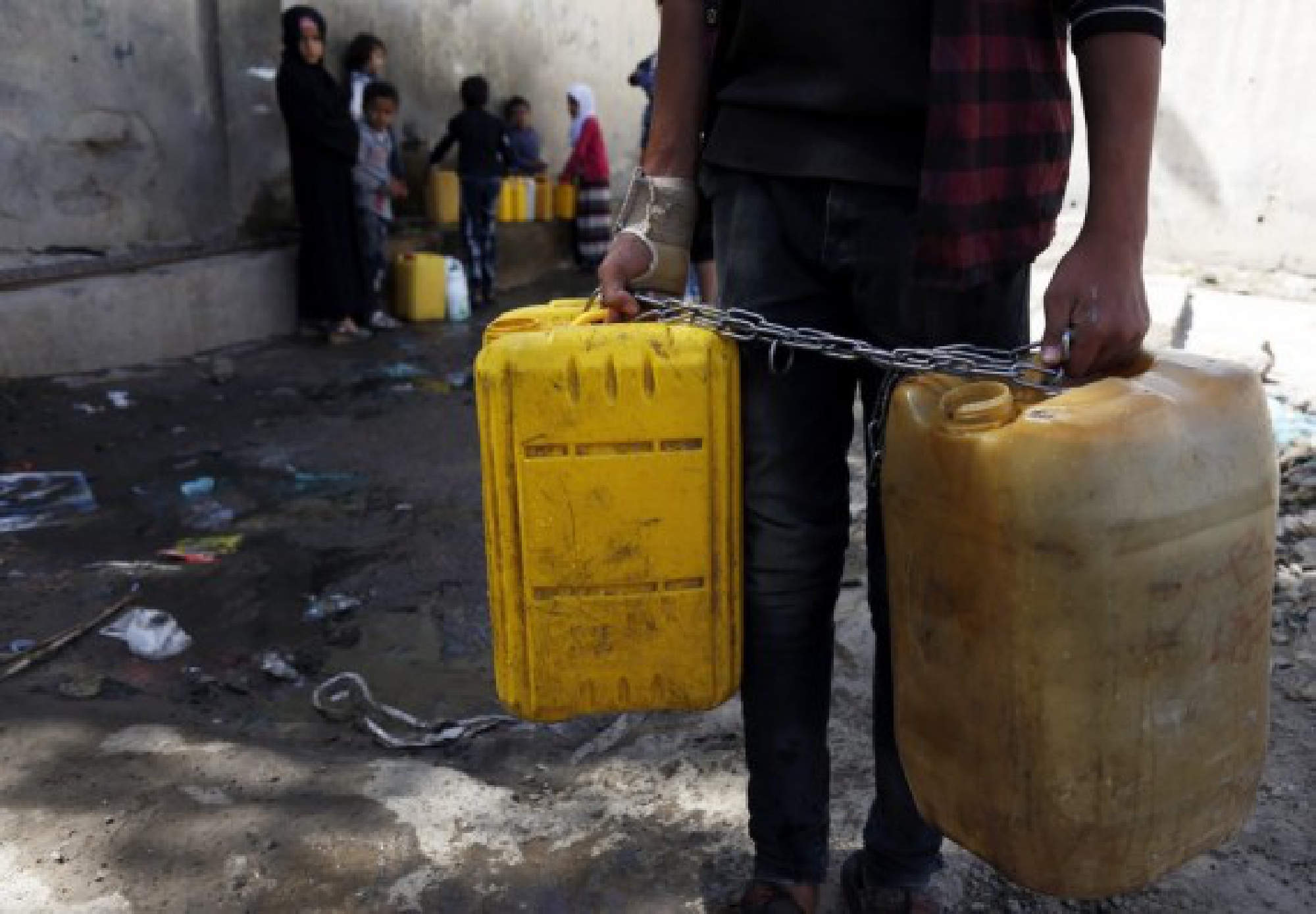 A Yemeni boy carries two plastic water barrels near a charity water tap in Sanaa, Yemen on Oct. 28, 2021. (Photo by Mohammed Mohammed/Xinhua)