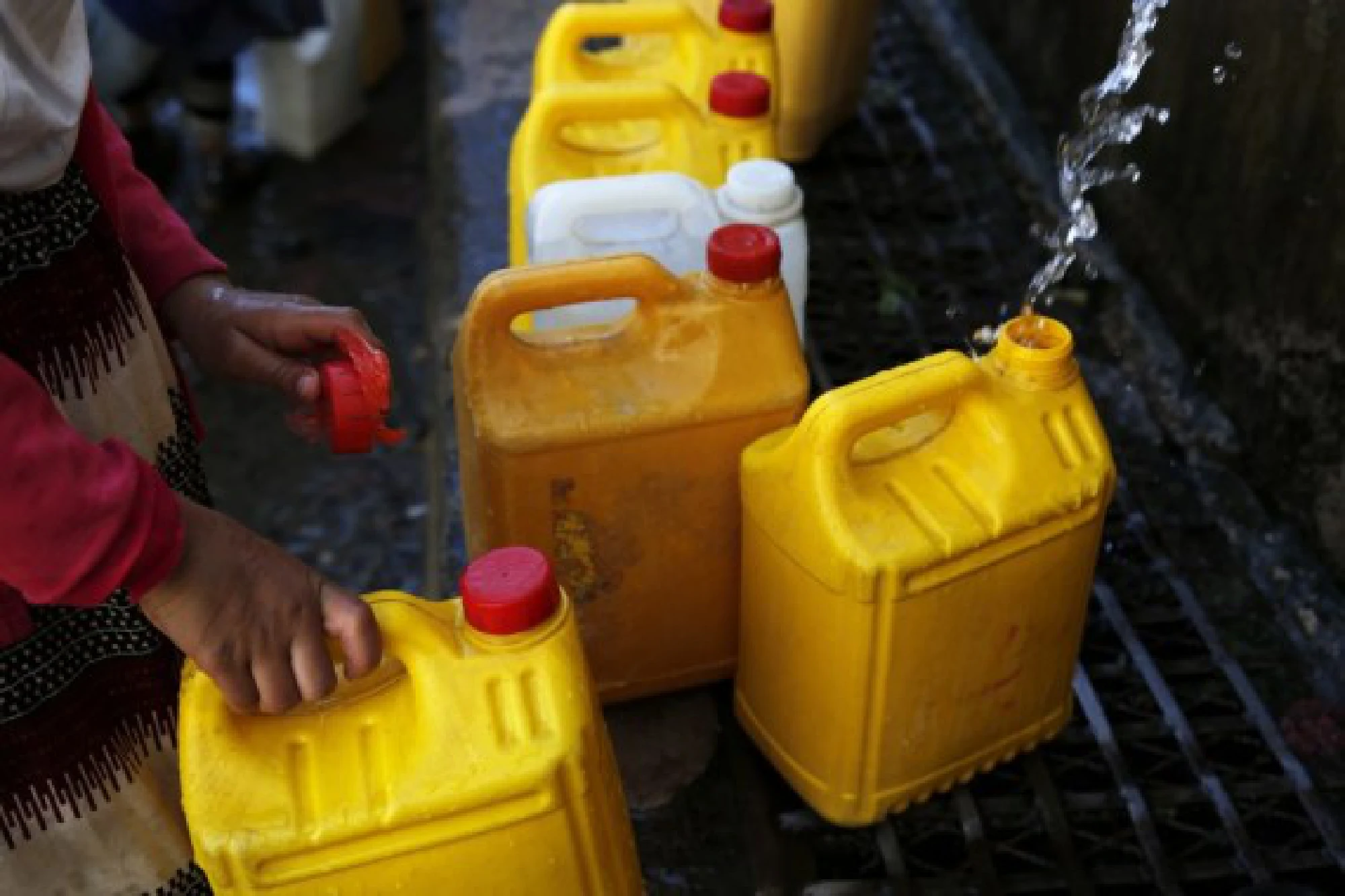 A Yemeni boy fills plastic barrels with water near a charity water tap in Sanaa, Yemen on Oct. 28, 2021. (Photo by Mohammed Mohammed/Xinhua)