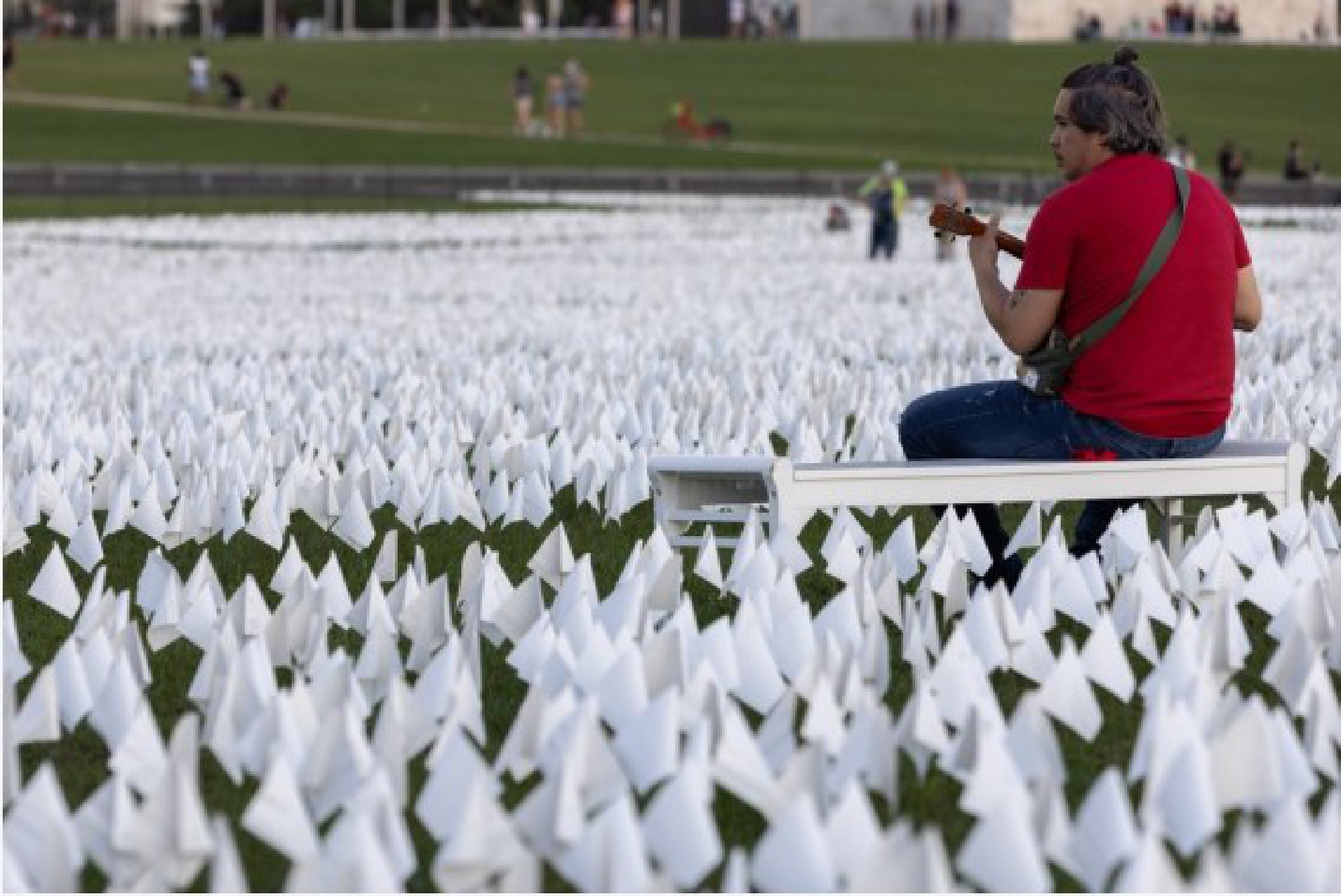 A man sits beside white flags placed on the National Mall to honor the lives lost to COVID-19 in Washington, D.C., the United States, Sept. 18, 2021. (Photo by Aaron Schwartz/Xinhua)