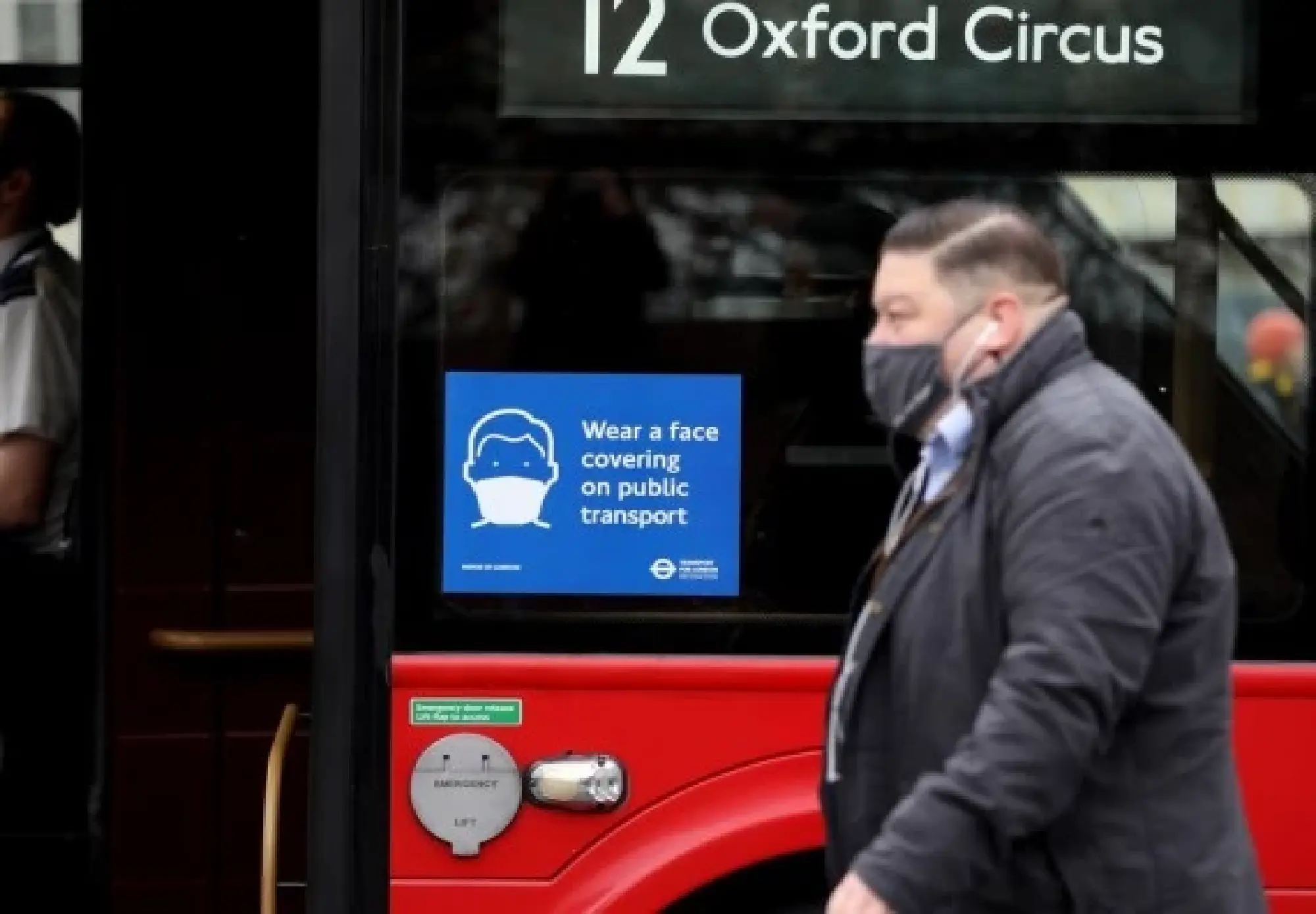 A man wearing a face mask walks past a bus in London, Britain, on Nov. 24, 2021. (Xinhua/Li Ying)