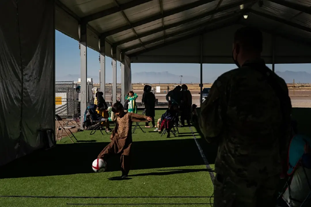 An Afghan boy plays soccer with a U.S military service member in a recreation center the refugee camp at Holloman Air Force Base in Alamogordo, N.M., on Nov. 4, 2021. MUST CREDIT: Washington Post photo by Salwan Georges
