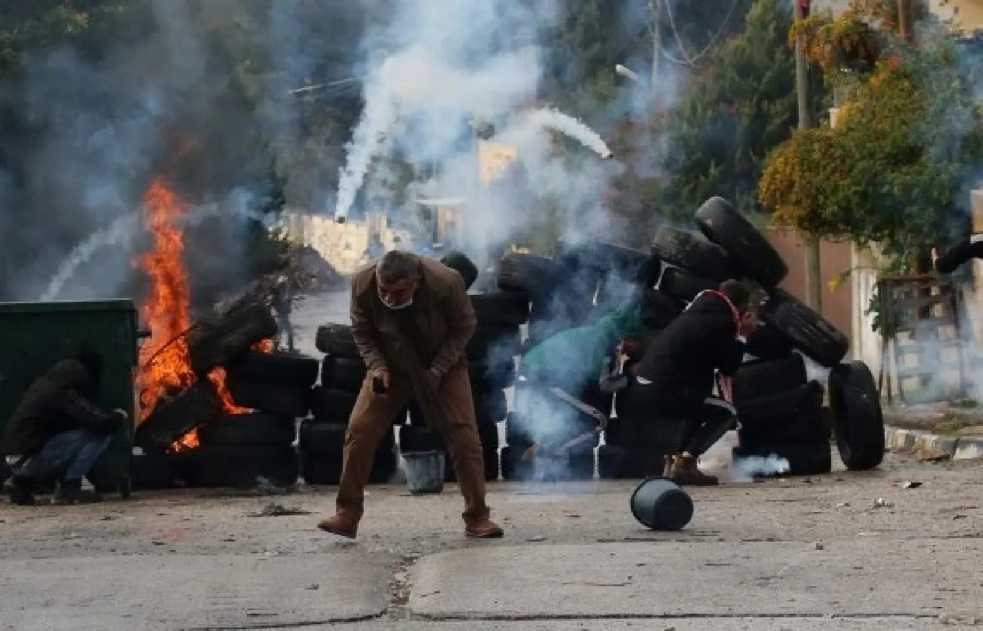 Palestinian protesters run to take cover from tear gas canisters fired by Israeli soldiers during clashes, in the village of Burqa, north of the West Bank city of Nablus, Dec. 23, 2021. (Photo by Nidal Eshtayeh/Xinhua)