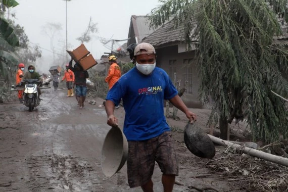 A man brings stuff from his house to a temporary shelter after Mount Semeru eruption in Lumajang, East Java, Indonesia, Dec. 5, 2021. (Photo by Bayu Novanta/Xinhua)
