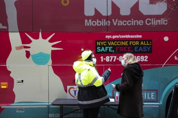 A staff worker talks with a woman outside a mobile vaccine clinic in New York, the United States, Dec. 7, 2021.(Xinhua/Wang Ying)
