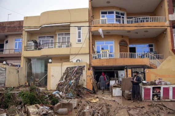 People clean a house after flash floods in Erbil, northern Iraq, on Dec. 17, 2021. (Photo by Dalshad Al-Daloo/Xinhua)