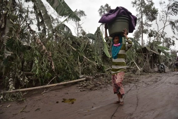 A woman brings stuff from her house to a temporary shelter after Mount Semeru eruption in Lumajang, East Java, Indonesia, Dec. 5, 2021. (Photo by Bayu Novanta/Xinhua)