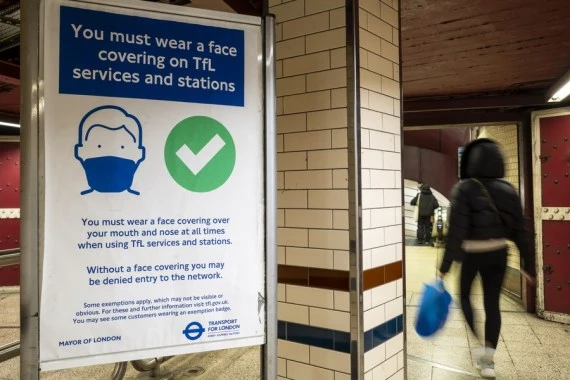 A commuter passes a sign requiring people to wear face covering while travelling on the tube in London, Britain, on Nov. 9, 2021.  (Photo by Stephen Chung/Xinhua)