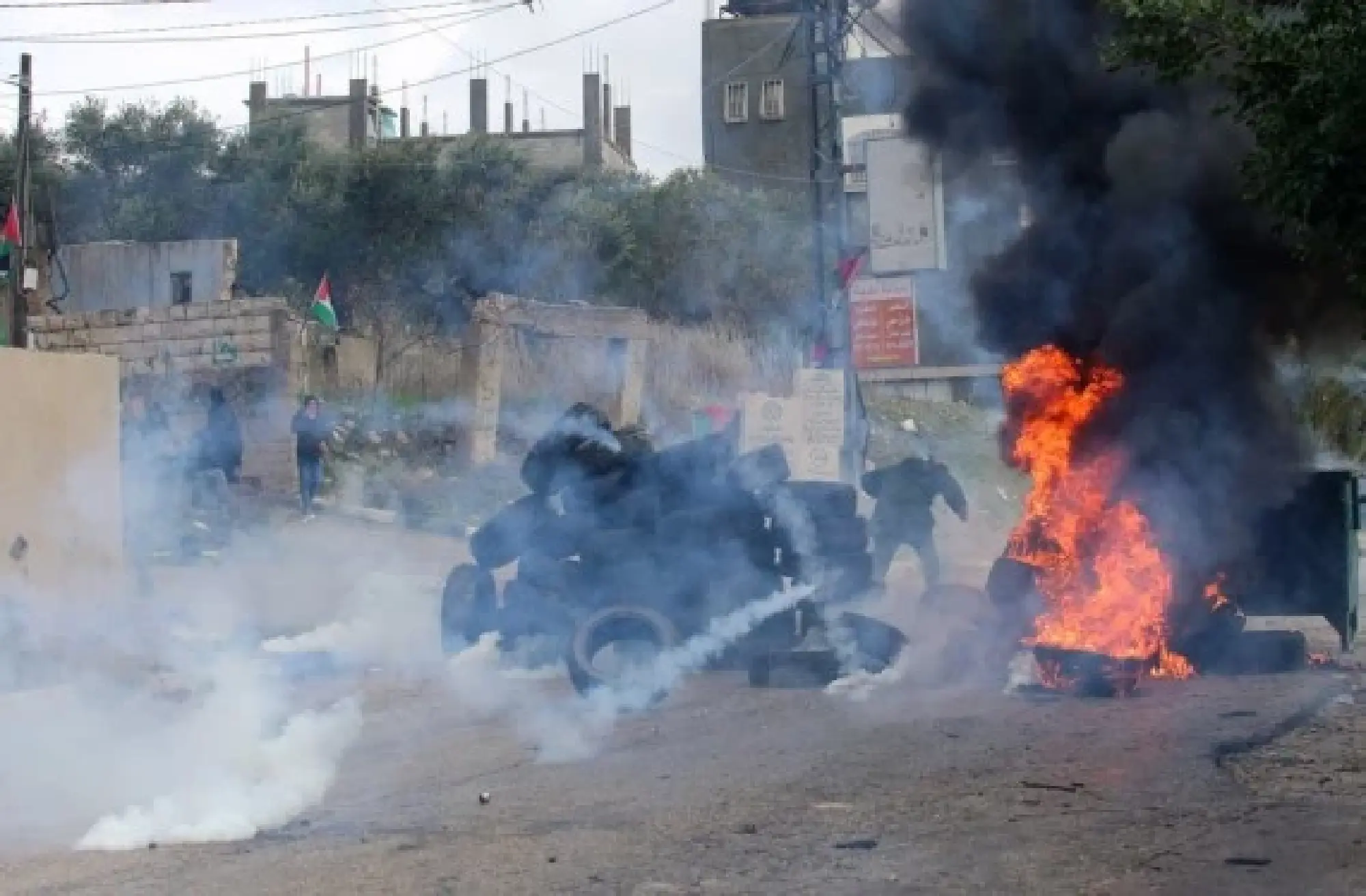 Palestinian protesters run to take cover from tear gas canisters fired by Israeli soldiers during clashes, in the village of Burqa, north of the West Bank city of Nablus, Dec. 23, 2021. (Photo by Nidal Eshtayeh/Xinhua)