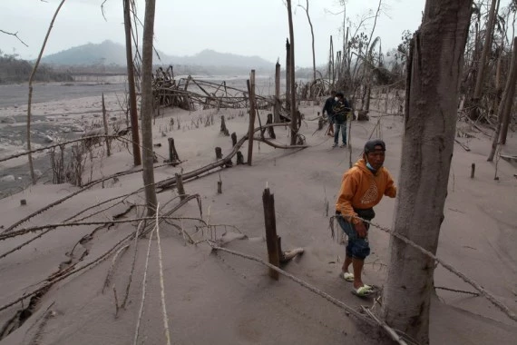 People walk on the ground covered by volcanic ash after Mount Semeru eruption in Lumajang, East Java, Indonesia, Dec. 5, 2021. (Photo by Bayu Novanta/Xinhua)