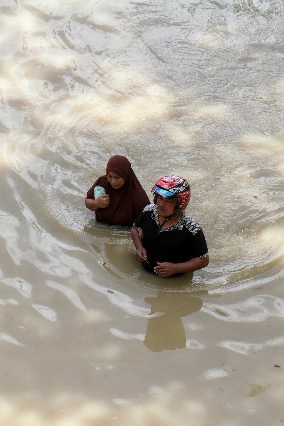 People wade through floodwater in Lhoksukon of Aceh Province, Indonesia, Jan. 4, 2022. (Photo by Fachrul Reza/Xinhua)