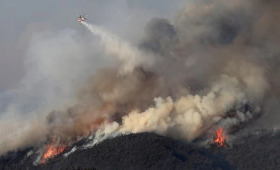 Photo taken on Feb. 16, 2022 shows a firefighting helicopter dropping water on a forest fire on a mountain in Yeongdeok, some 350 km southeast of the capital Seoul, South Korea. (NEWSIS/Handout via Xinhua)