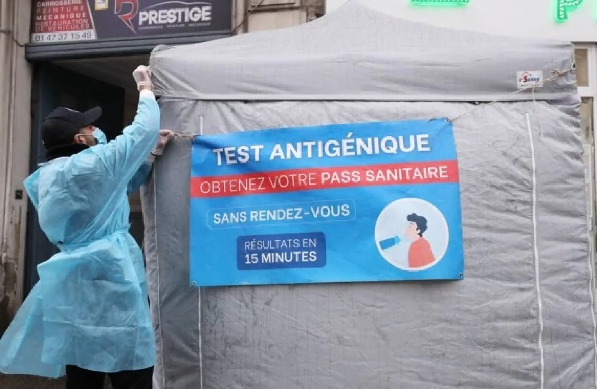 A medical staff member adjusts a sign in the wind at a fast COVID-19 test screening tent in Paris, France, April 1, 2022. (Xinhua/Gao Jing)