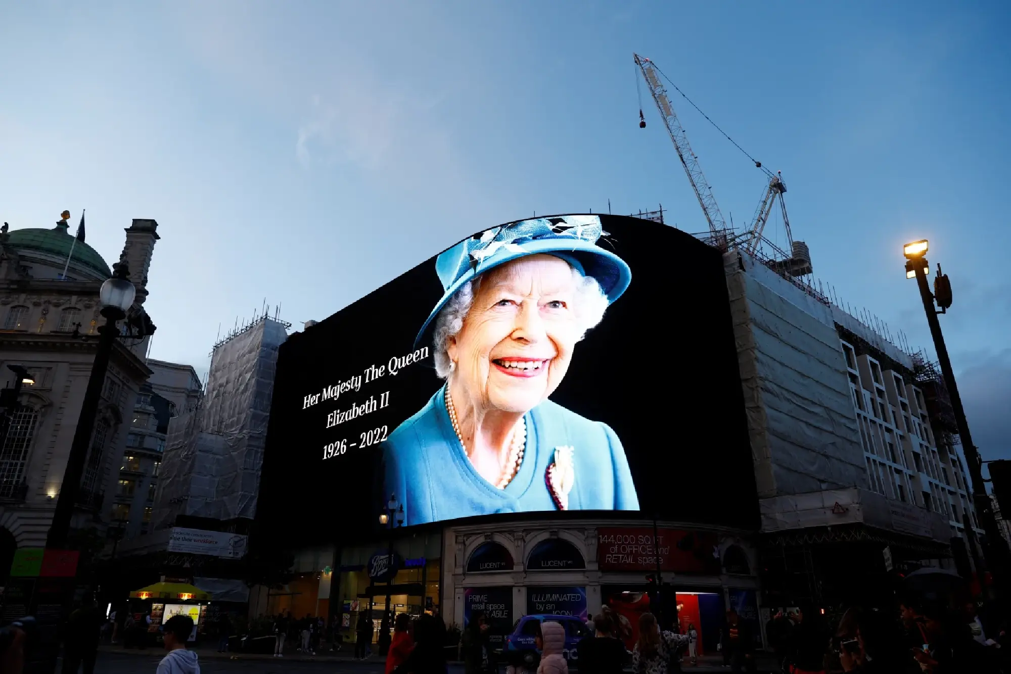 People embrace as an image of Queen Elizabeth, Britain's longest-reigning monarch and the nation's figurehead for seven decades is displayed at Piccadilly Circus after she died aged 96, according to Buckingham Palace, in London, Britain September 8, 2022. REUTERS/Andrew Boyers