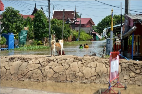 People wade through a flooded street in Ayutthaya, Thailand, on Oct. 18, 2022. 