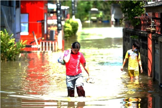 People wade through a flooded street in Ayutthaya, Thailand, on Oct. 18, 2022.