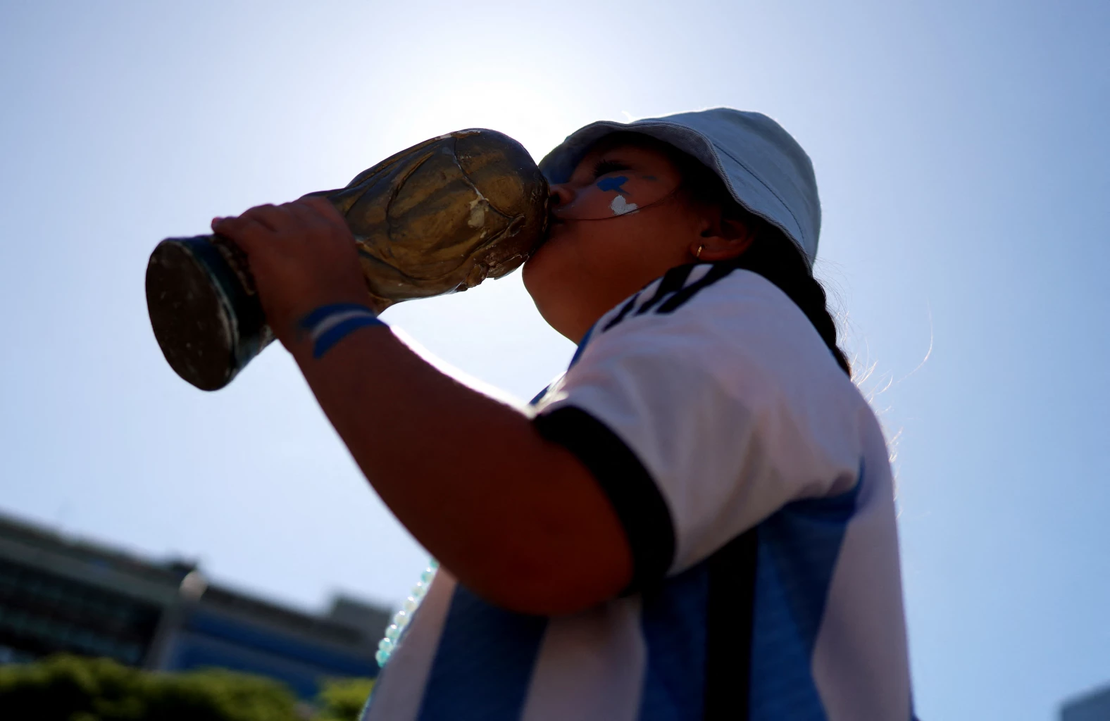 General view as a Argentina fan kisses a replica trophy ahead of the victory parade