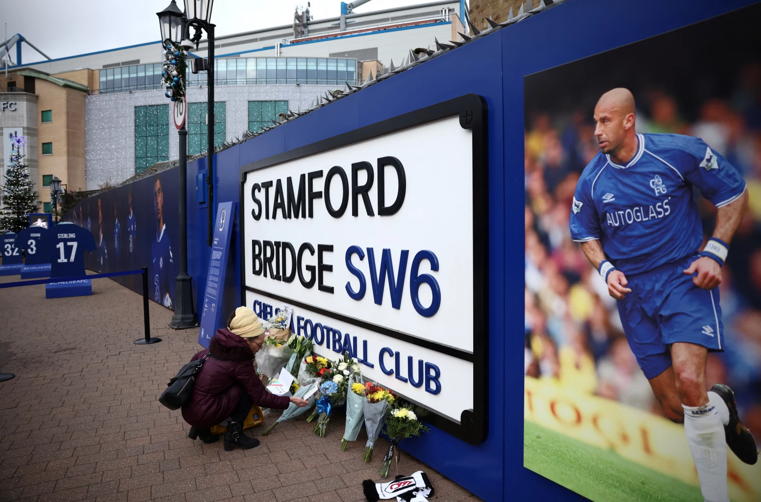 A person lays flowers next to a photo of Gianluca Vialli outside Stamford Bridge, the stadium of Chelsea Football Club, in London, Britain