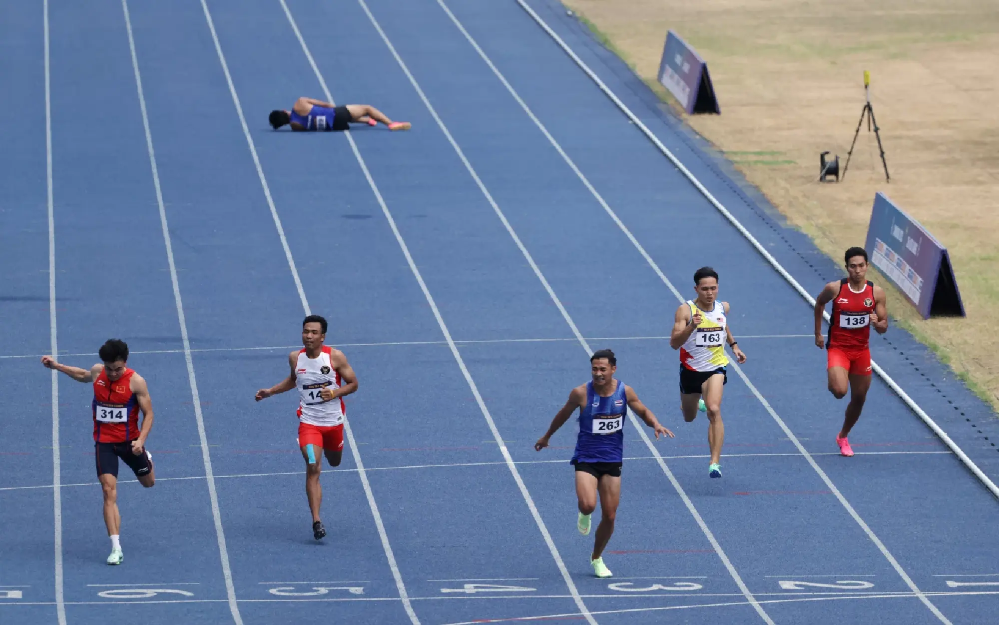 Thailand's Soraoat Dapbang and Malaysia's Jonathan Myepa in action during the men's 200m final as Thailand's Puripol Boonson goes down injured