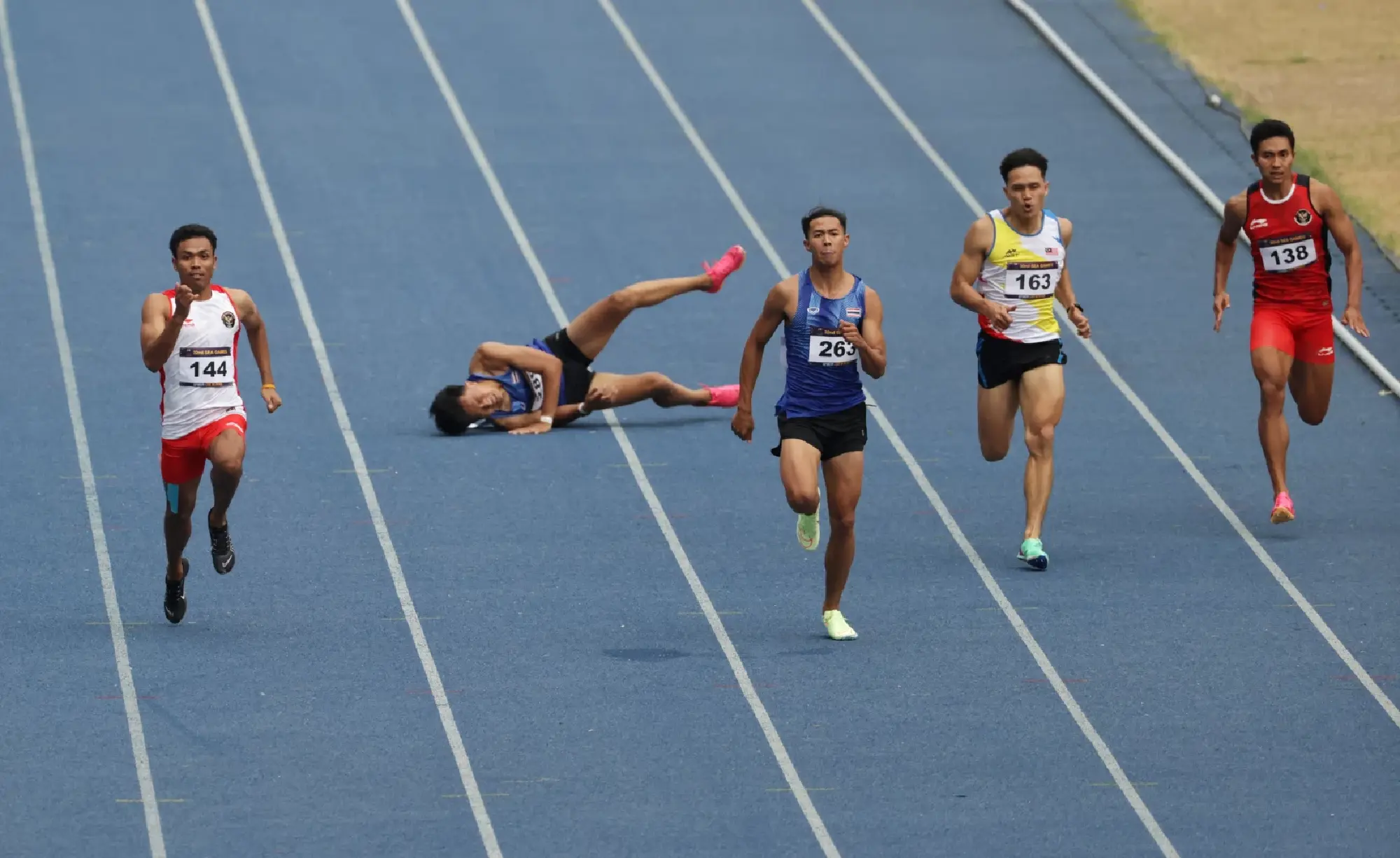 Thailand's Soraoat Dapbang and Malaysia's Jonathan Myepa in action during the men's 200m final as Thailand's Puripol Boonson goes down injured