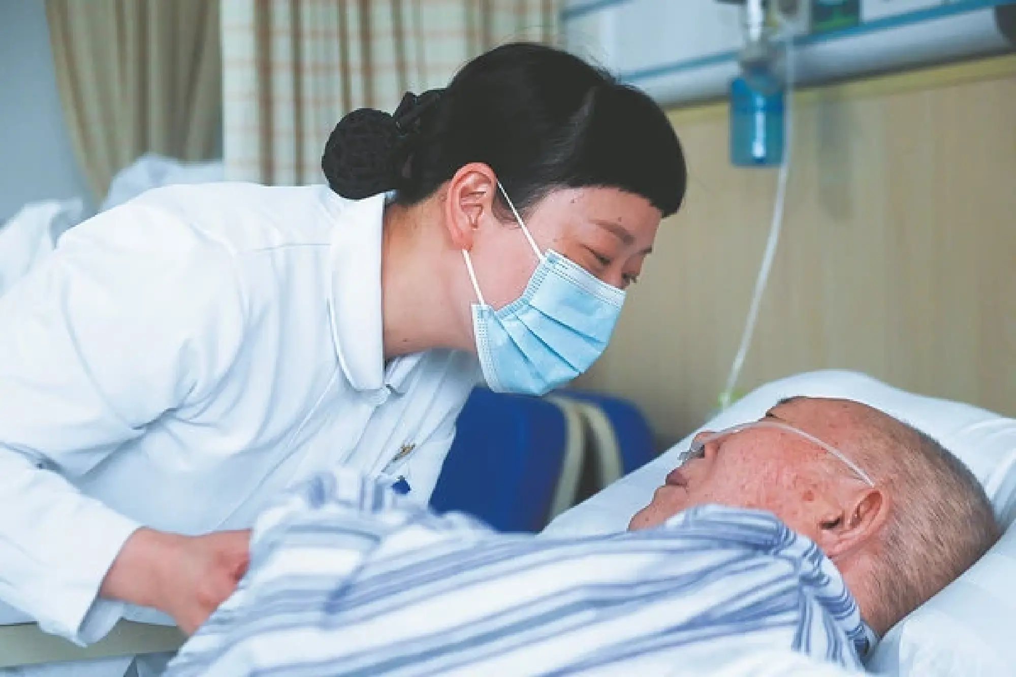 Xiang Qiaozhen, head nurse of the hospice ward, talks with a patient. [Photo/Xinhua]