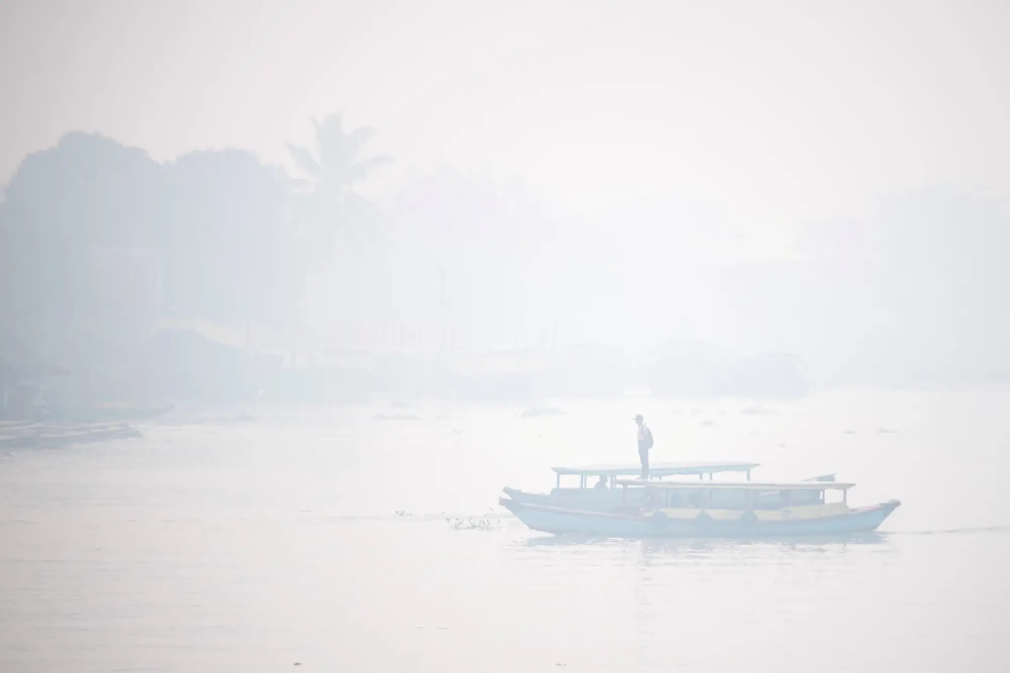 Students ride a wooden boat through the Ogan river, which is covered by smog due to wildfires, in Palembang, South Sumatra province, Indonesia, September 30, 2023, in this photo taken by Antara Foto. Antara Foto/Nova Wahyudi/ via REUTERS ATTENTION EDITORS