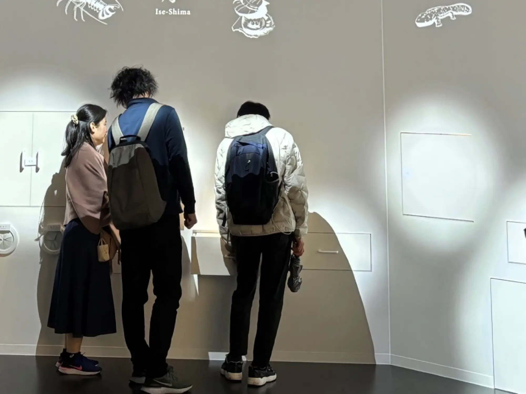 Visitors explore products from Mie Prefecture by opening drawers built into the walls of the Kansai Pavilions Mie booth at the Osaka Expo.
