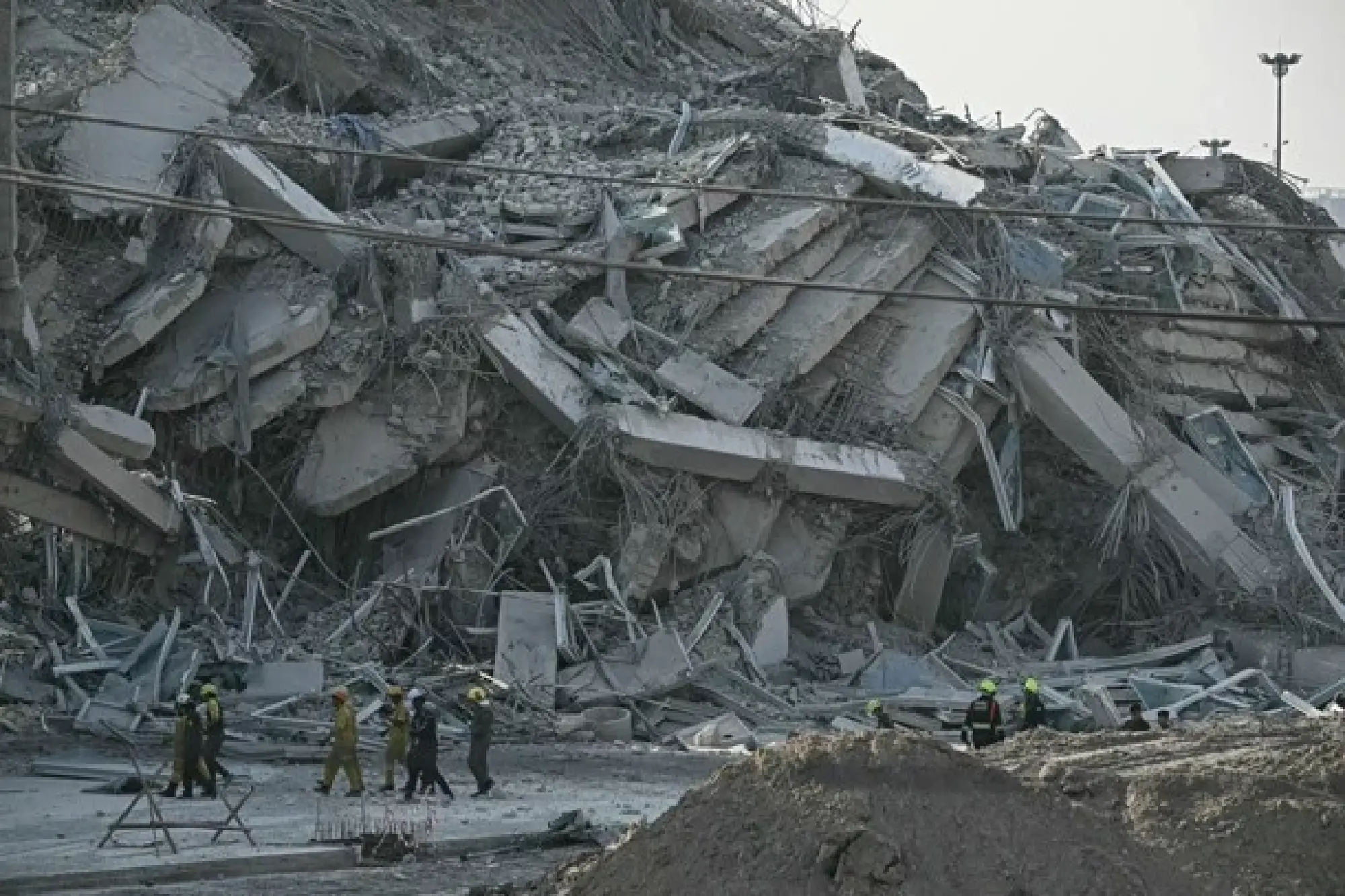 Rescue workers walk past debris of a construction site after a building collapsed in Bangkok on March 28, 2025. (c) AFP-Jiji