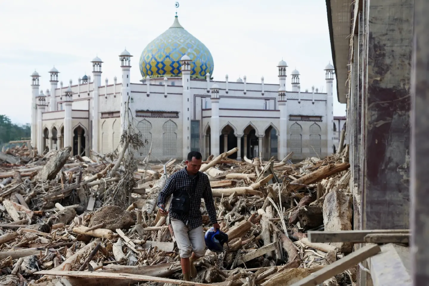 Indonesians climb over logs in walk to aid centre as flood deaths rise over 900